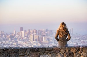 Woman sits on wall looking out over a city